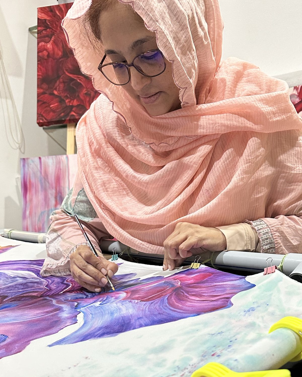 Husna Rafath K. painting a floral design on silk